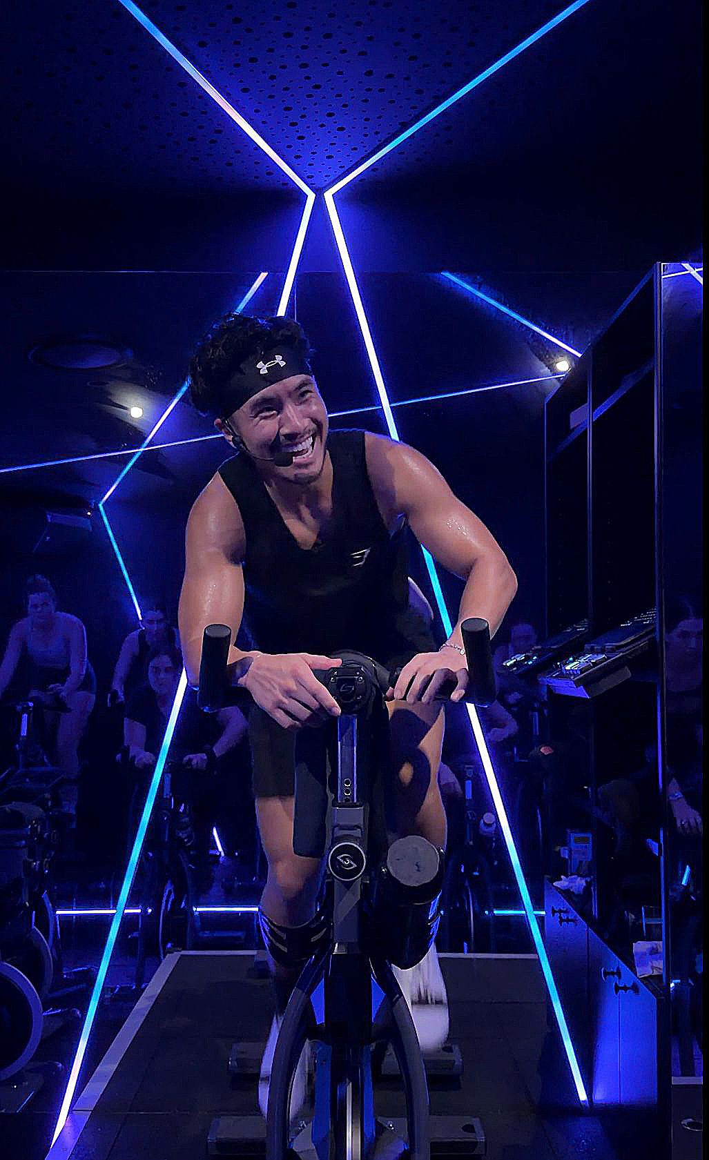 Coach Jesse riding out of the saddle under red neon in the Soultrain Ride Room, Woolloomooloo