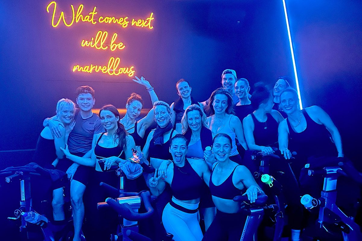 Soultrain ride class smiling together under the 'What comes next will be marvellous' neon sign