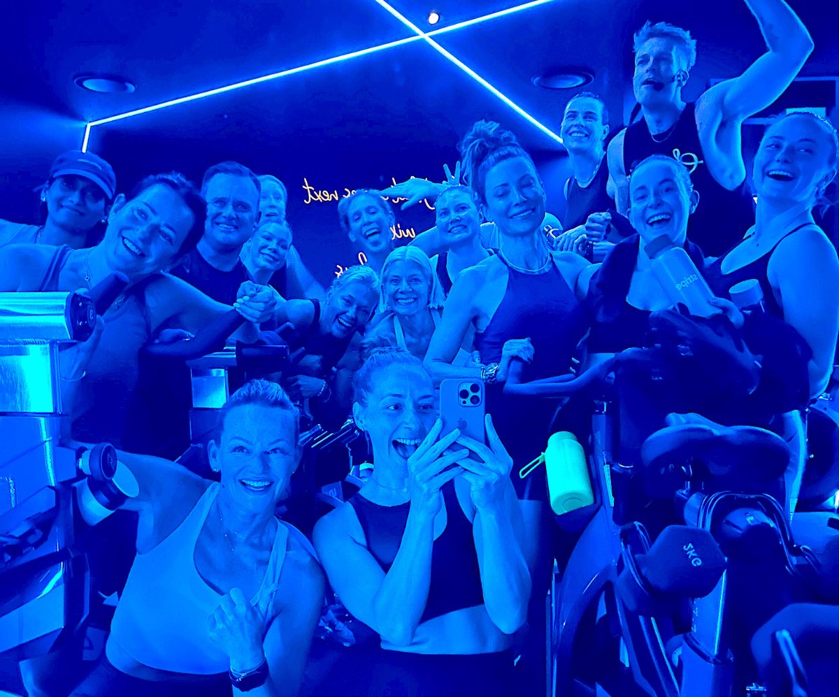 Full Soultrain ride class packed in for a celebratory group photo in the neon-lit room